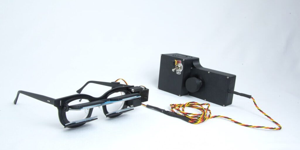 PrPeriscoping glasses setup connected to a control box with wires, developed by Chadwick Optical.totype glasses connected to a black control box with wires and an on/off switch, used for engineering or optical testing at Chadwick Optical.