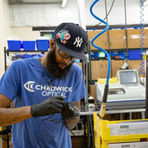 lab-staff-3 Ken at Chadwick Optical, wearing a Chadwick Optical t-shirt and gloves, working on eyeglass frames in the lab.