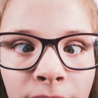 misalignment Close-up of a young girl wearing glasses with eyes misaligned, indicating a potential binocular vision issue.