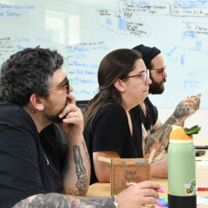 office-staff-8 Chadwick Optical team members, attentively listening in a meeting, with a whiteboard full of notes in the background.